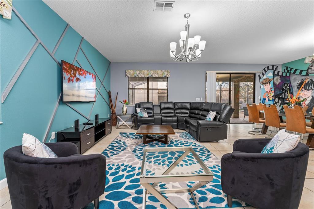 A living room features a blue accent wall, black leather sectional, and patterned area rug — 9158 WEDGE DRIVE, DAVENPORT, FL