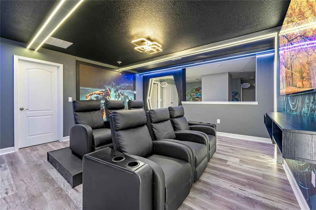 A home theater room features tiered rows of black leather recliners and LED accent lighting — 9158 WEDGE DRIVE, DAVENPORT, FL