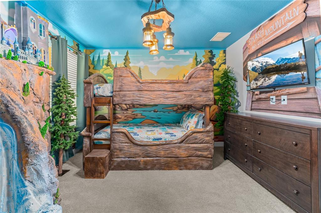 A themed bedroom features a log-style bunk bed, a mural, and a wall-mounted television — 9158 WEDGE DRIVE, DAVENPORT, FL