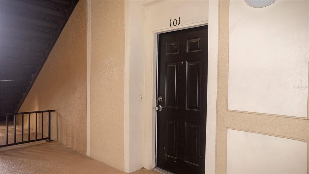 A dark brown apartment door labeled 101 is situated in an outdoor hallway — 6466 CAVA ALTA DRIVE UNIT 101, ORLANDO, FL