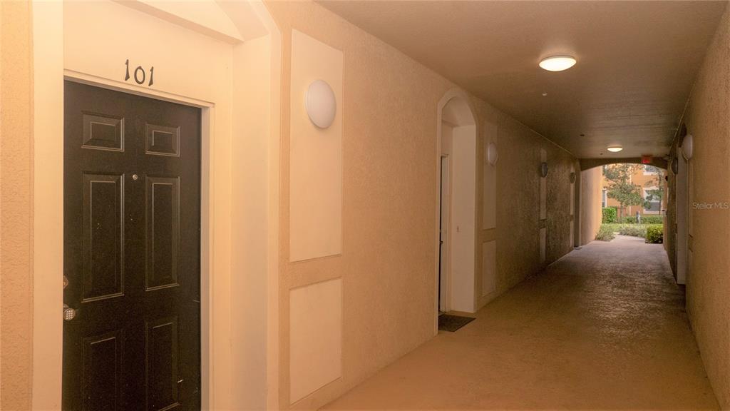 A covered outdoor walkway leads to the entrance of apartment unit 101 — 6466 CAVA ALTA DRIVE UNIT 101, ORLANDO, FL