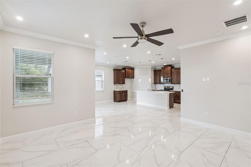 An open-concept kitchen and living area features dark wood cabinets, white countertops, and marble-look flooring — 520 LEMON STREET, AUBURNDALE, FL