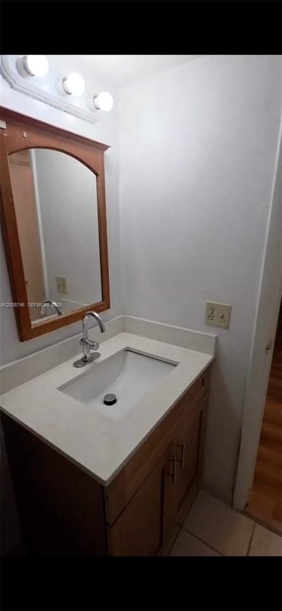 A bathroom vanity features a white countertop, a wooden cabinet, and a framed mirror — 1700 NW 58th Ter # 3M, Sunrise FL 33313, SUNRISE, FL