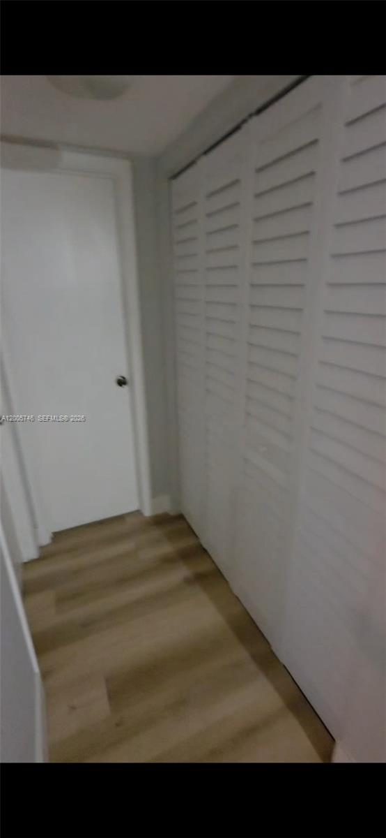A hallway features light wood-look flooring, a white door, and white louvered closet doors — 1700 NW 58th Ter # 3M, Sunrise FL 33313, SUNRISE, FL