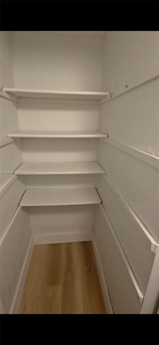 A walk-in closet features white walls, light wood-look flooring, and four built-in shelves — 1700 NW 58th Ter # 3M, Sunrise FL 33313, SUNRISE, FL