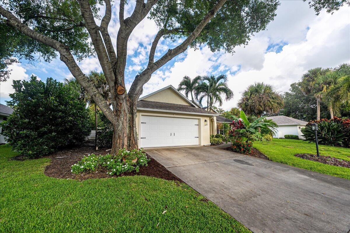 A single-story house with a white garage door, a concrete driveway, and a large tree — 109 39th Drive, Vero Beach FL 32968, VERO BEACH, FL