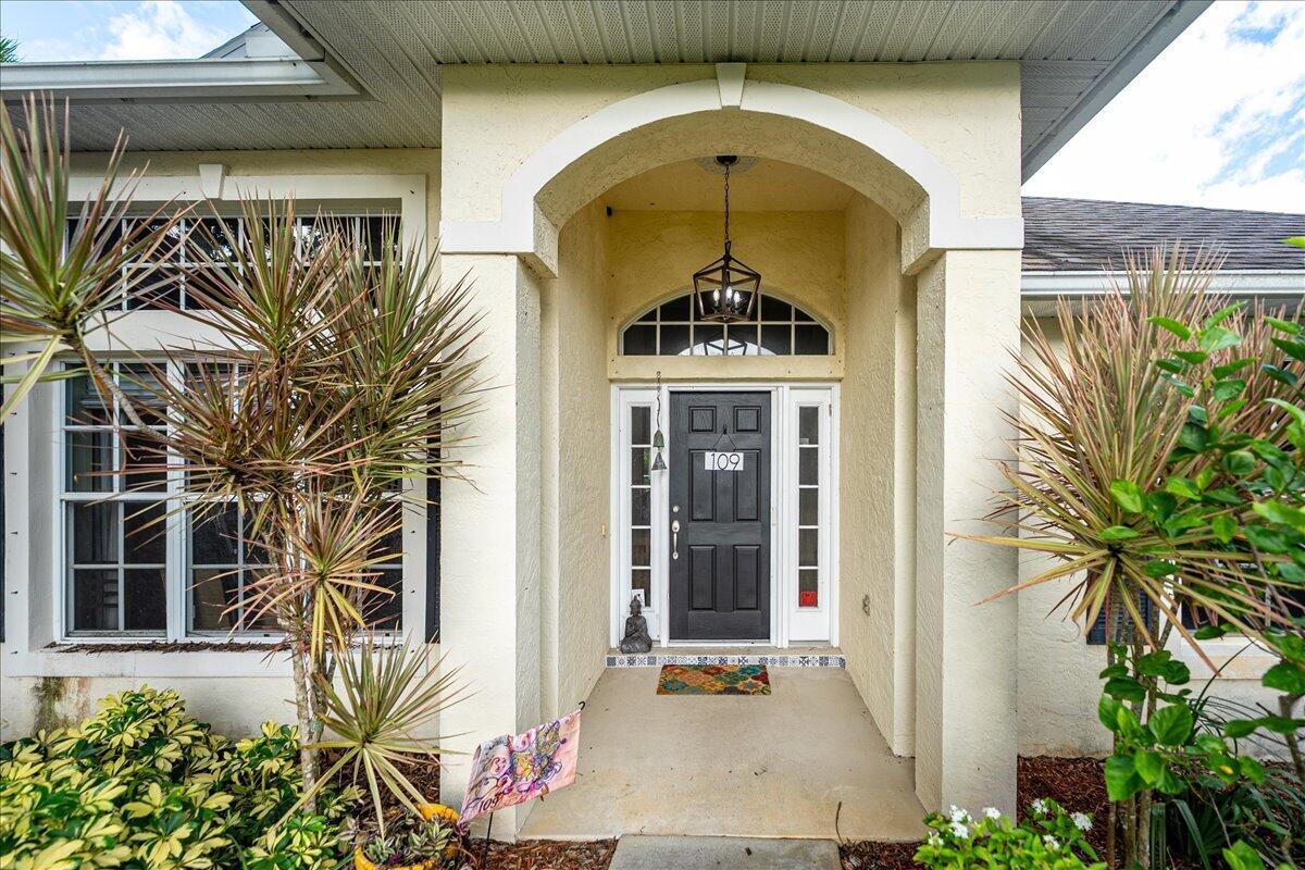 The exterior view shows a covered entryway with a black front door and arched transom — 109 39th Drive, Vero Beach FL 32968, VERO BEACH, FL