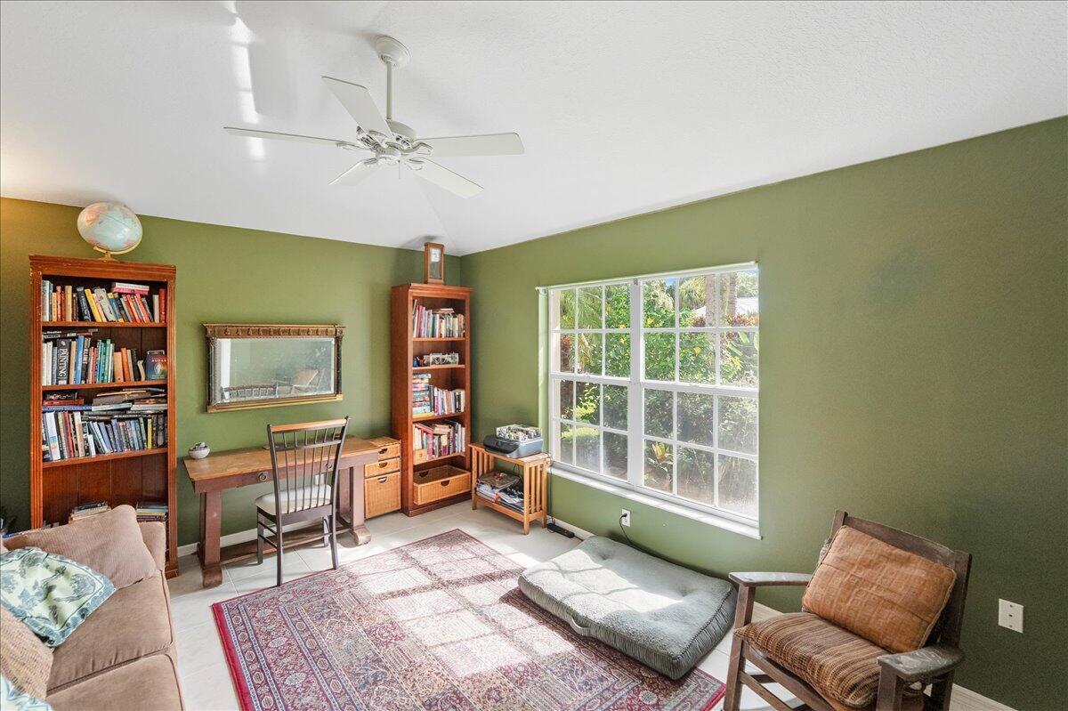 A home office with green walls, two wooden bookcases, a desk, and a large window — 109 39th Drive, Vero Beach FL 32968, VERO BEACH, FL