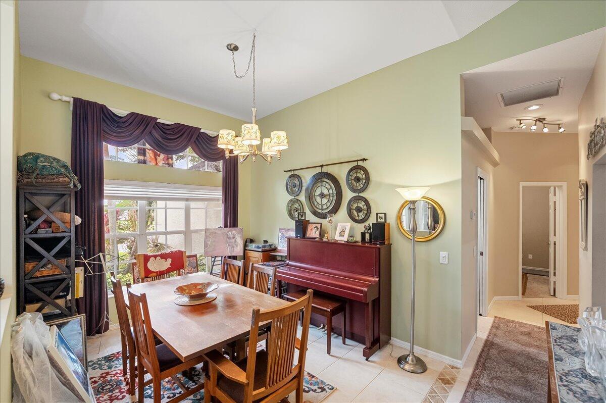 A dining room features a wooden table, chairs, an upright piano, and a chandelier — 109 39th Drive, Vero Beach FL 32968, VERO BEACH, FL