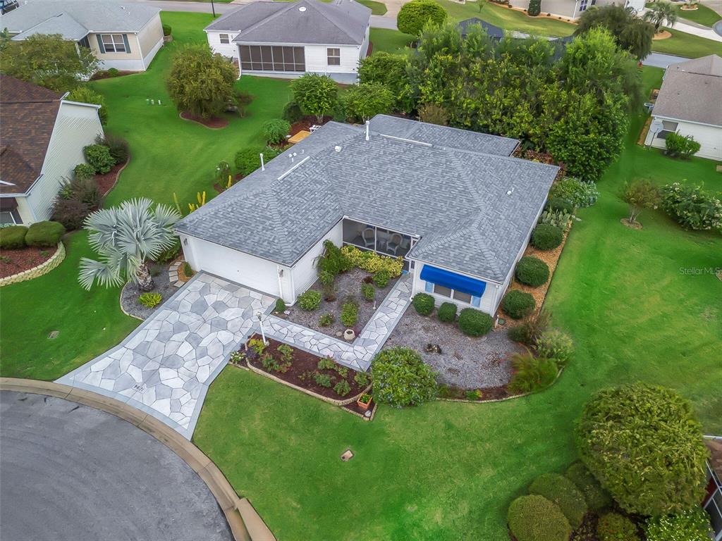 An aerial view shows a single-story house with a gray roof, stone driveway, and landscaping — 9671 SE 168TH MAPLESONG LANE, THE VILLAGES, FL