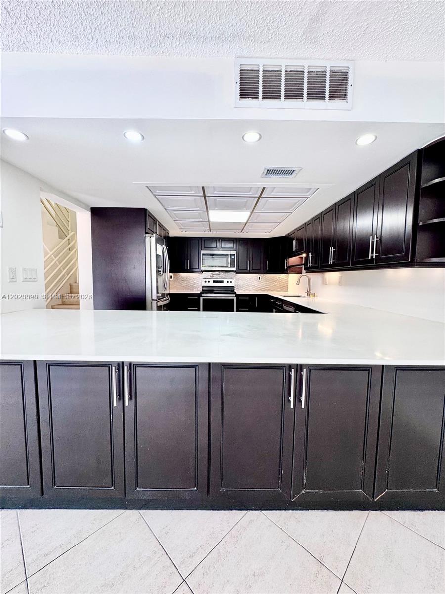 A kitchen features dark cabinetry, white countertops, and a coffered ceiling with recessed lighting — 535 NW 98th Ave, Plantation FL 33324, PLANTATION, FL