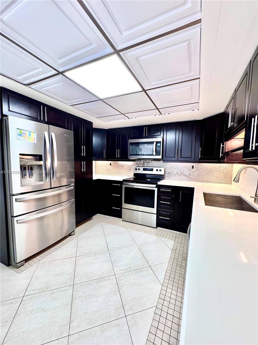 A kitchen features dark wood cabinets, stainless steel appliances, white countertops, and a coffered ceiling — 535 NW 98th Ave, Plantation FL 33324, PLANTATION, FL