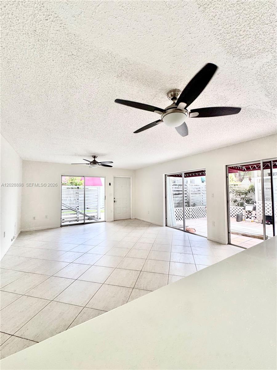 An open living area features white tile floors, two ceiling fans, and sliding glass doors — 535 NW 98th Ave, Plantation FL 33324, PLANTATION, FL