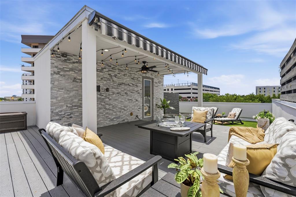A rooftop deck features a covered seating area with a stone wall and fire pit — 300 DELMAR TERRACE S, ST PETERSBURG, FL