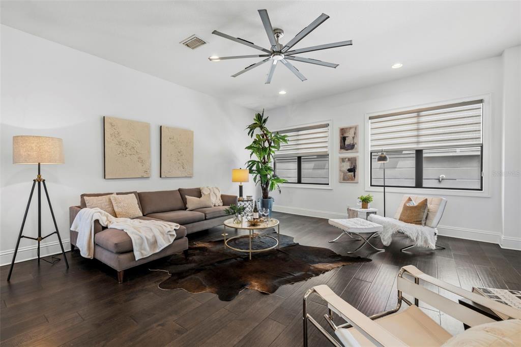 A living room features a brown sectional sofa, a cowhide rug, and a large ceiling fan — 300 DELMAR TERRACE S, ST PETERSBURG, FL