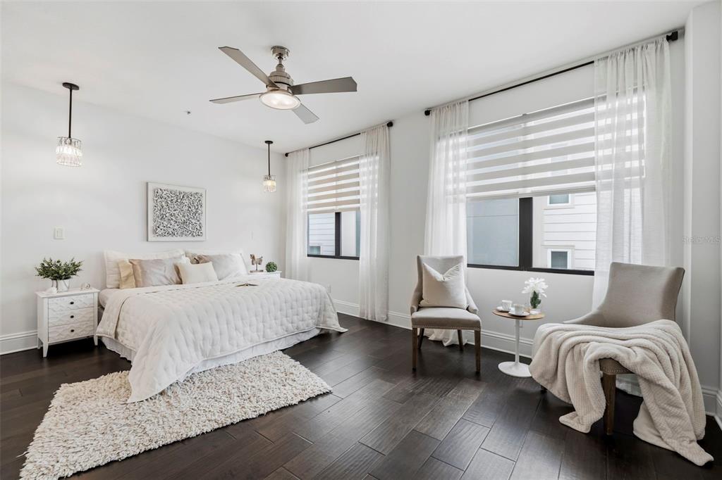 A bright bedroom features a bed, two chairs, dark wood floors, and large windows — 300 DELMAR TERRACE S, ST PETERSBURG, FL