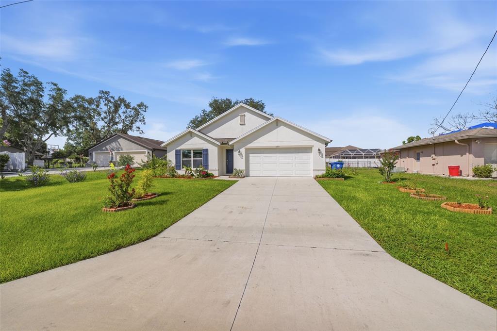 A single-story house with a white exterior, a two-car garage, and a concrete driveway — 11215 MURRAYSVILLE DRIVE, SPRING HILL, FL