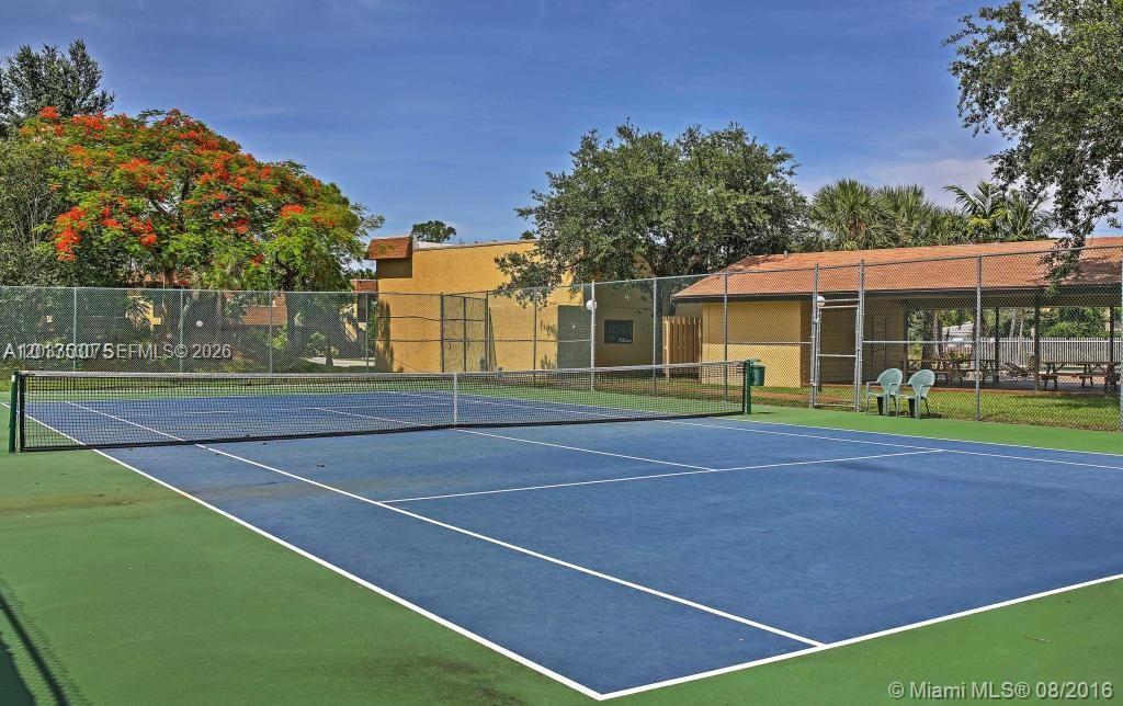 A blue tennis court is enclosed by a chain-link fence with a covered seating area — 1265 S Flagler Ave # 217, Pompano Beach FL 33060, POMPANO BEACH, FL