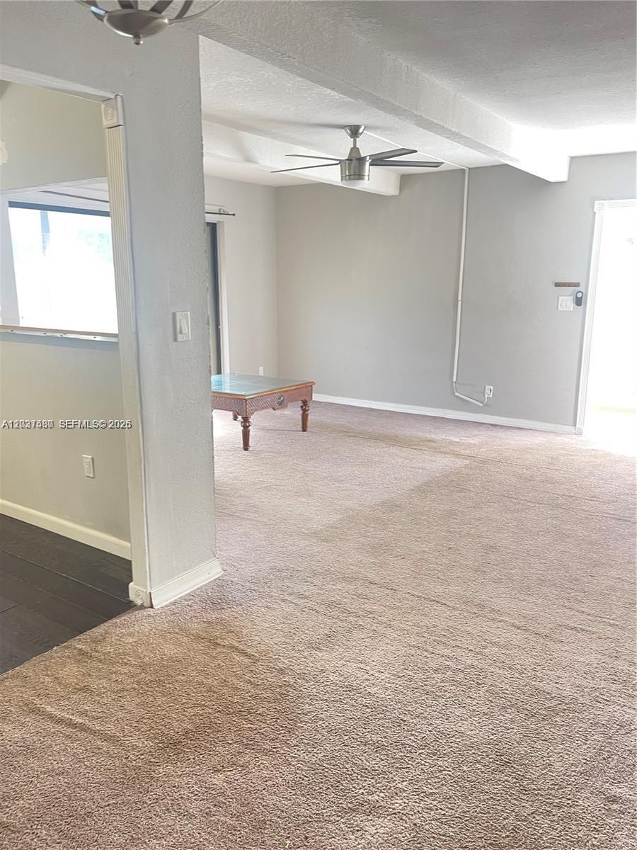 This living area features beige carpeting, a ceiling fan, and a glass-topped coffee table — 1265 S Flagler Ave # 217, Pompano Beach FL 33060, POMPANO BEACH, FL