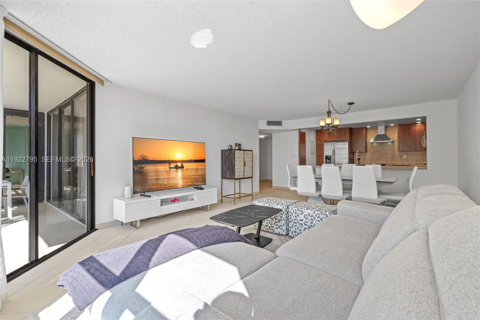 A living room with a sectional sofa, television, and an adjacent dining area and kitchen — 1865 Brickell Ave # A1013, Miami FL 33129, MIAMI, FL