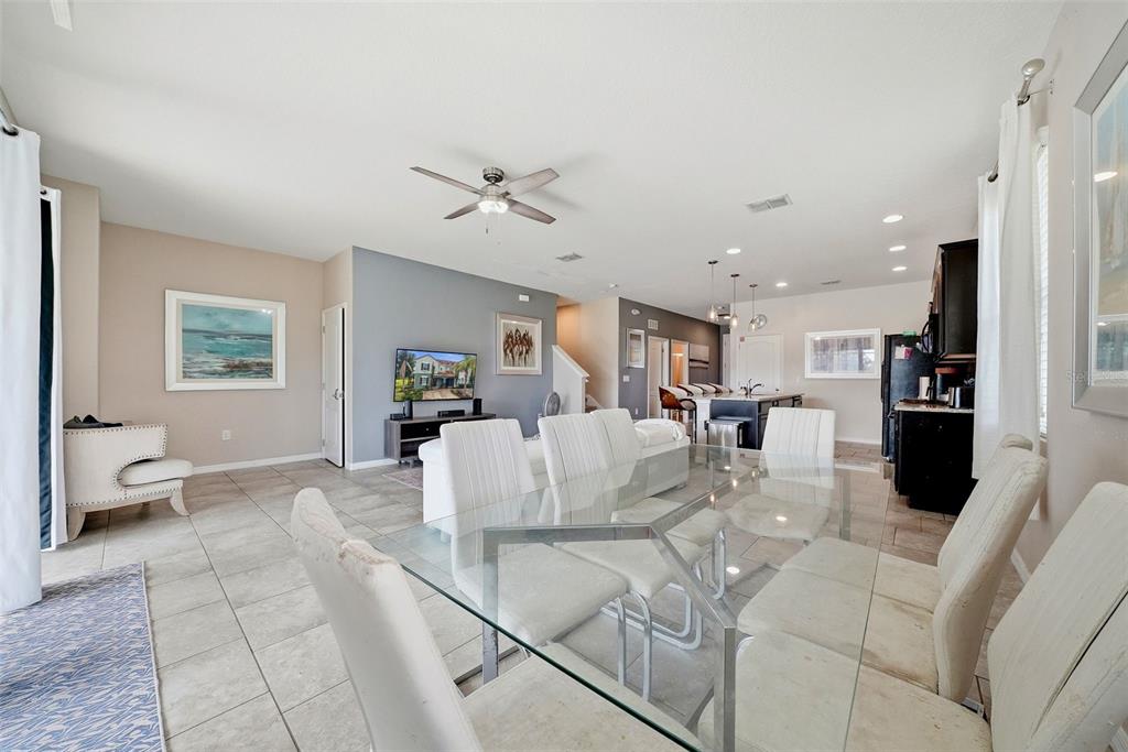 An open-concept living and dining area features tile flooring, a glass table, and kitchen island — 4715 TERRASONESTA DRIVE, DAVENPORT, FL