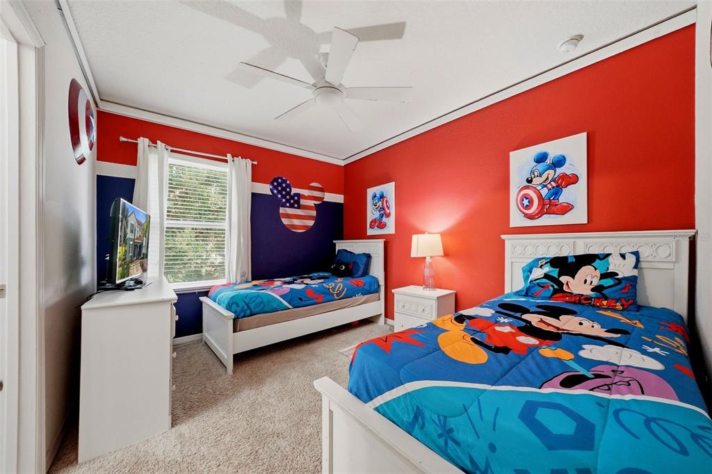 A bedroom features two twin beds with Mickey Mouse bedding, red walls, and a ceiling fan — 4715 TERRASONESTA DRIVE, DAVENPORT, FL
