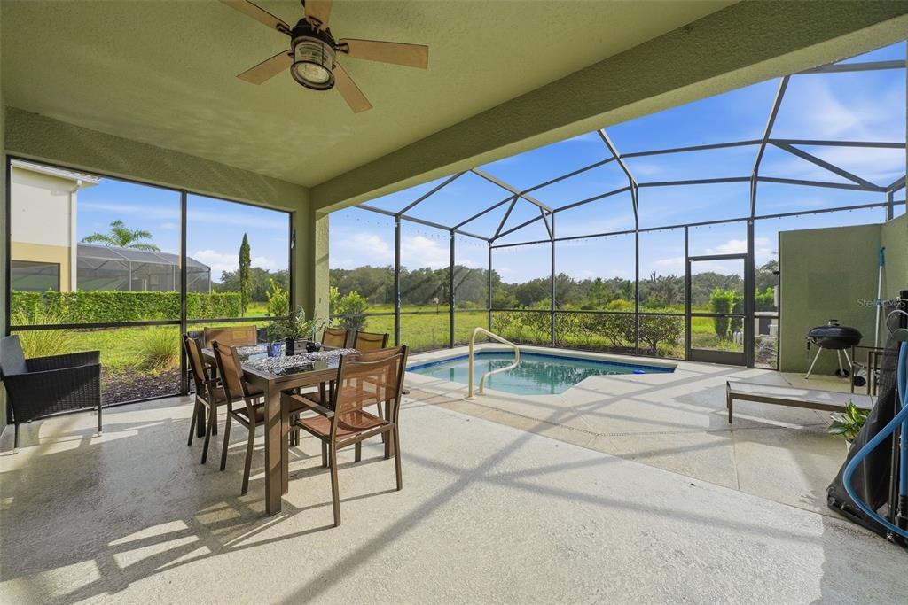 A covered patio features a dining set, a small swimming pool, and a screened enclosure — 4715 TERRASONESTA DRIVE, DAVENPORT, FL