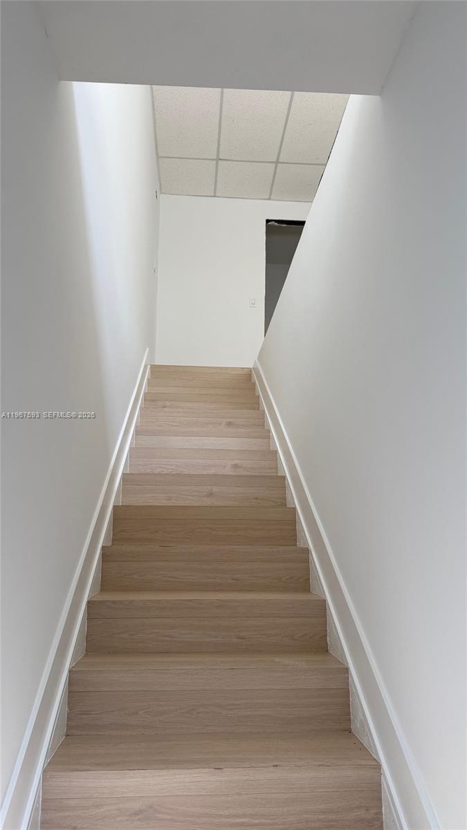 A staircase with light wood-look steps leads upward between two plain white walls — 12237 SW 132nd Ct # 10, Miami FL 33186, MIAMI, FL