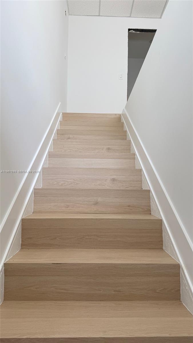 A straight staircase features light wood-look treads and white walls with baseboard trim — 12237 SW 132nd Ct # 10, Miami FL 33186, MIAMI, FL