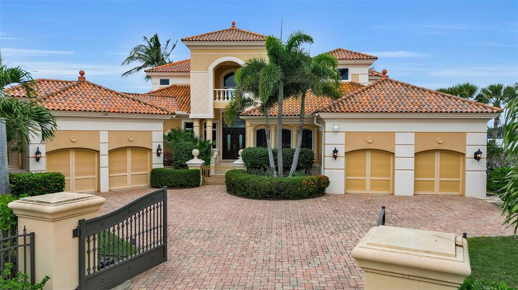 A two-story Mediterranean-style house with a brick driveway, four garage doors, and palm trees — 1541 CARIBBEAN DRIVE, SARASOTA, FL