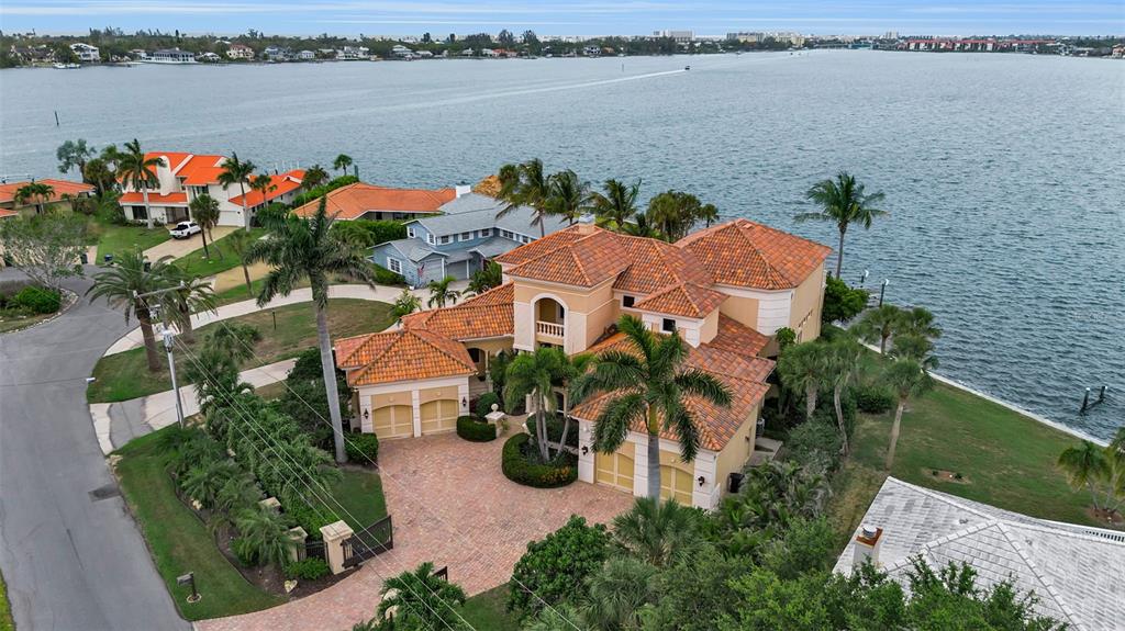 An aerial view shows a large waterfront house with a tiled roof and brick driveway — 1541 CARIBBEAN DRIVE, SARASOTA, FL