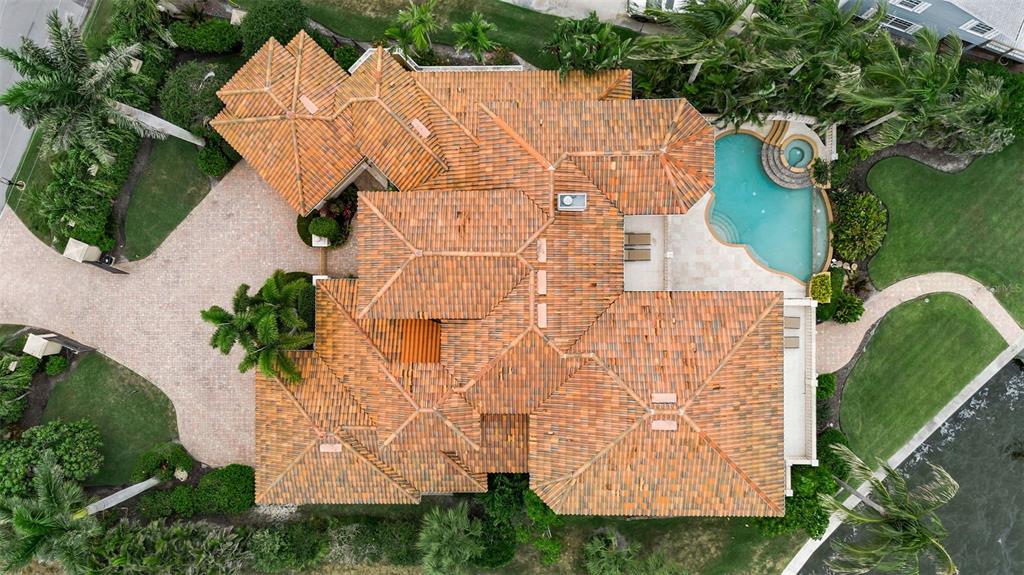 An aerial view shows a large house with a tiled roof, pool, and waterfront lawn — 1541 CARIBBEAN DRIVE, SARASOTA, FL