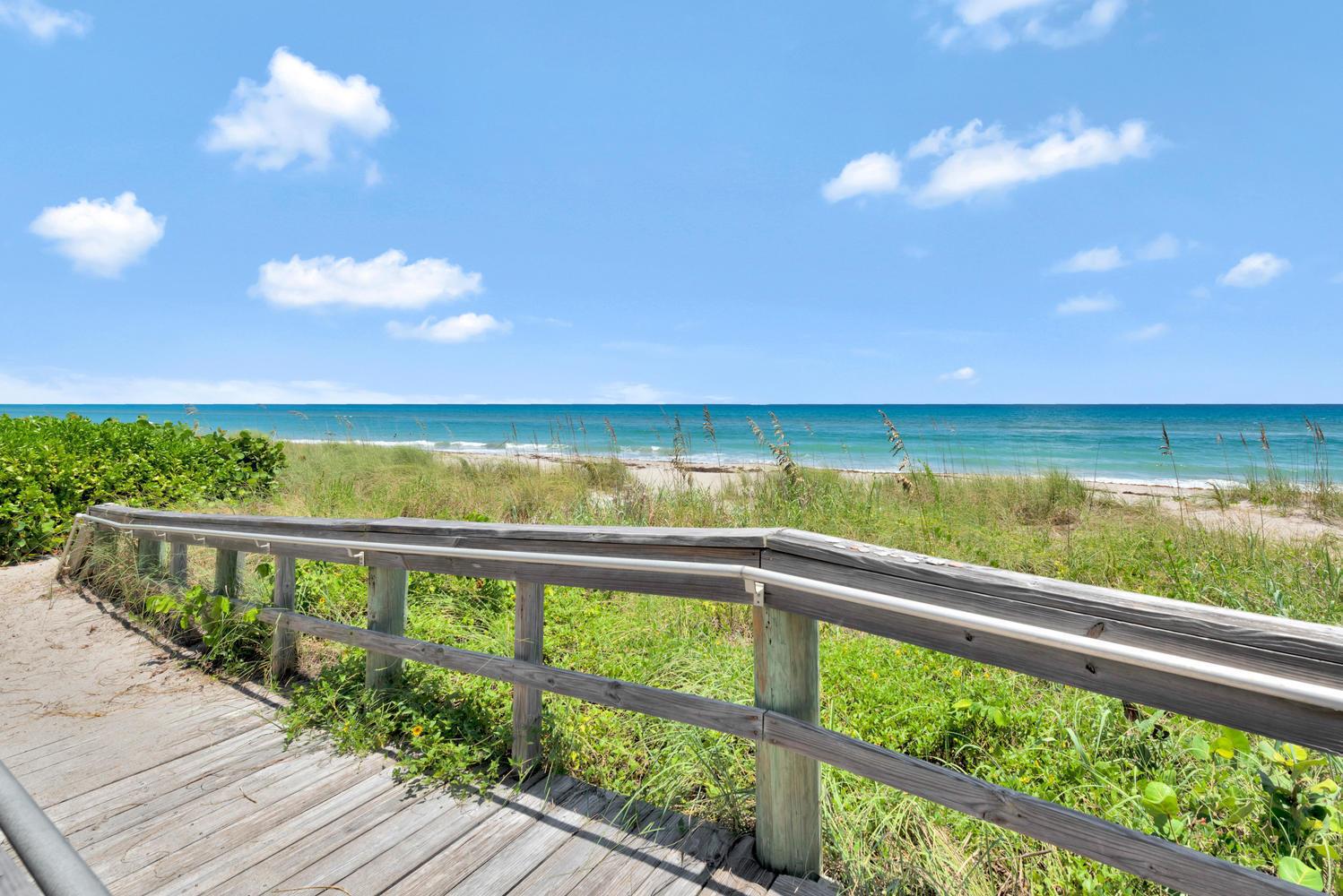 A wooden boardwalk with railings leads toward a sandy beach and the ocean — 530 Ocean Drive # 202, Juno Beach FL 33408, JUNO BEACH, FL