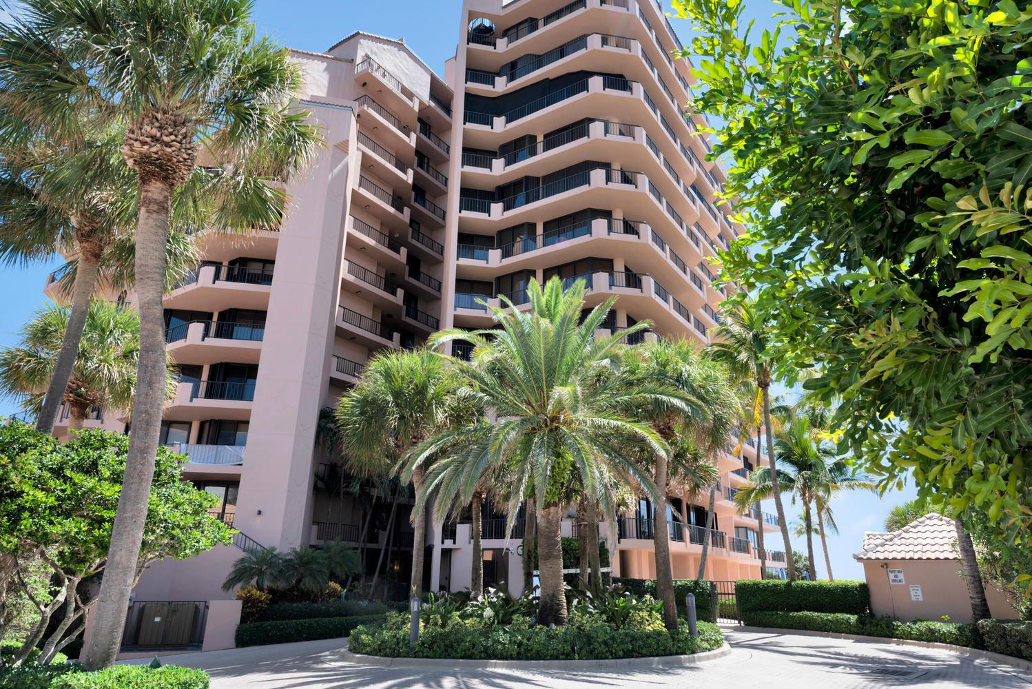 A tall, pink multi-story apartment building is surrounded by palm trees and lush landscaping — 530 Ocean Drive # 202, Juno Beach FL 33408, JUNO BEACH, FL