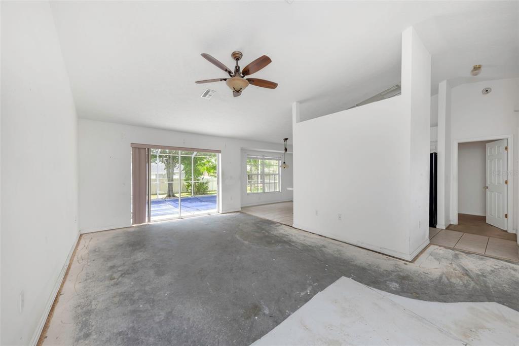 An empty living room with concrete floors, a ceiling fan, and a sliding glass door — 7919 STARFIRE WAY, NEW PORT RICHEY, FL