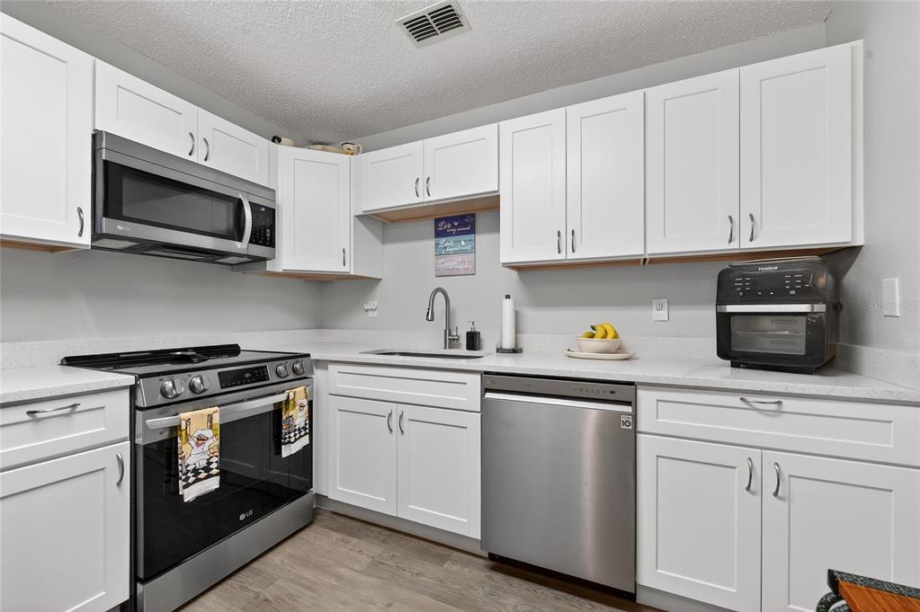 A kitchen features white cabinets, stainless steel appliances, and light-colored countertops — 1601 BIG TREE ROAD UNIT 101, SOUTH DAYTONA, FL