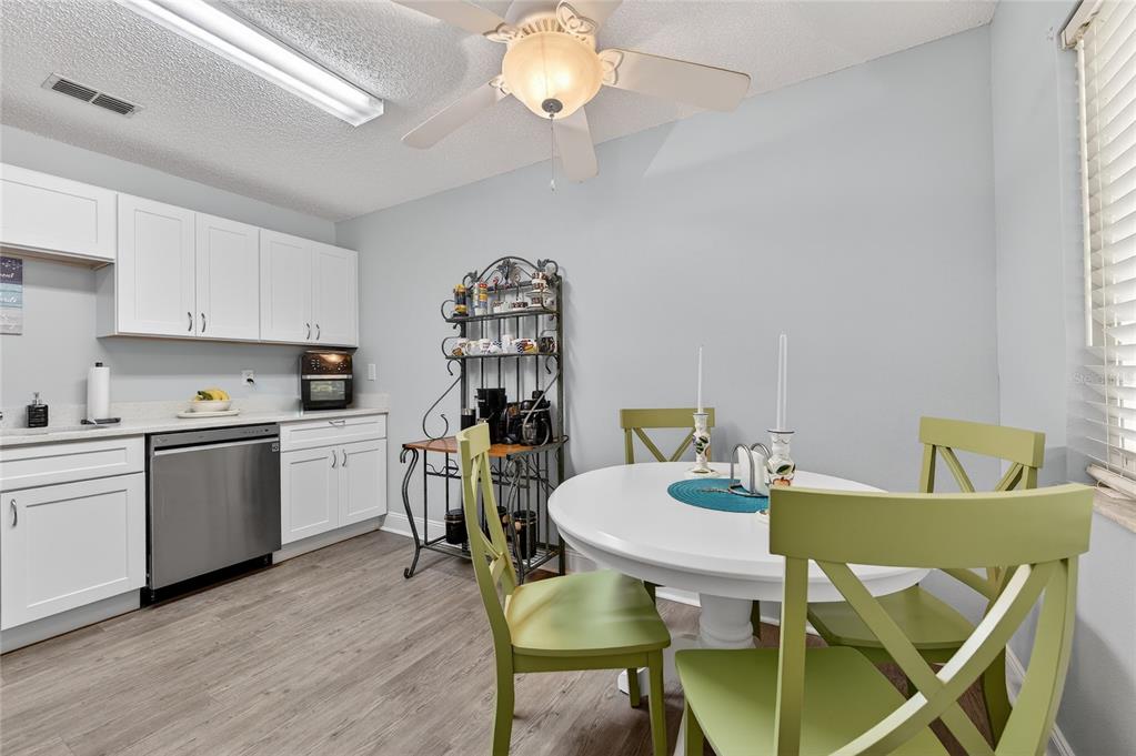 A kitchen with white cabinets, stainless steel appliances, and a round dining table with chairs — 1601 BIG TREE ROAD UNIT 101, SOUTH DAYTONA, FL