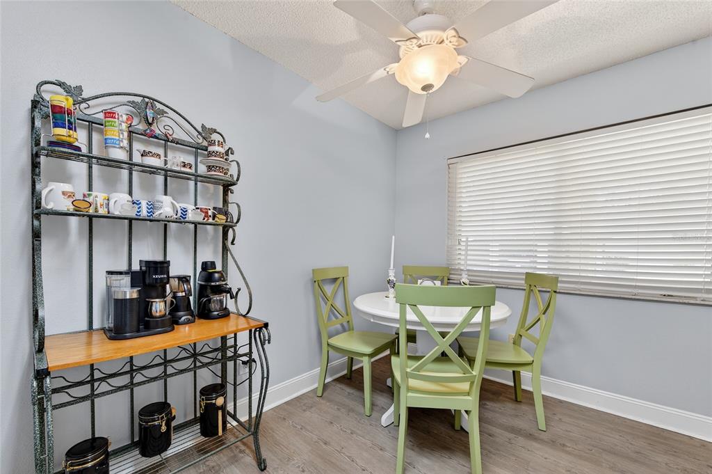A dining area features a metal baker's rack, a white round table, and green chairs — 1601 BIG TREE ROAD UNIT 101, SOUTH DAYTONA, FL