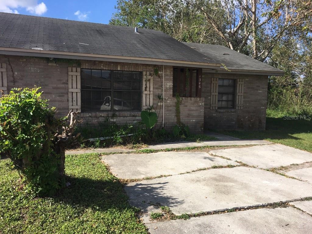 A single-story brick house with a gray shingled roof and a cracked concrete driveway — 1305-1307 FAIRWAY DRIVE, LAKELAND, FL