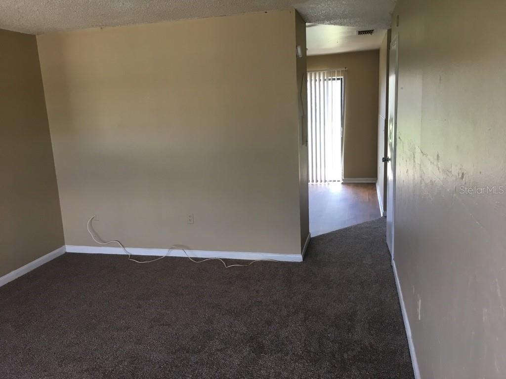 A carpeted living room leads to a hallway with a sliding glass door — 1305-1307 FAIRWAY DRIVE, LAKELAND, FL