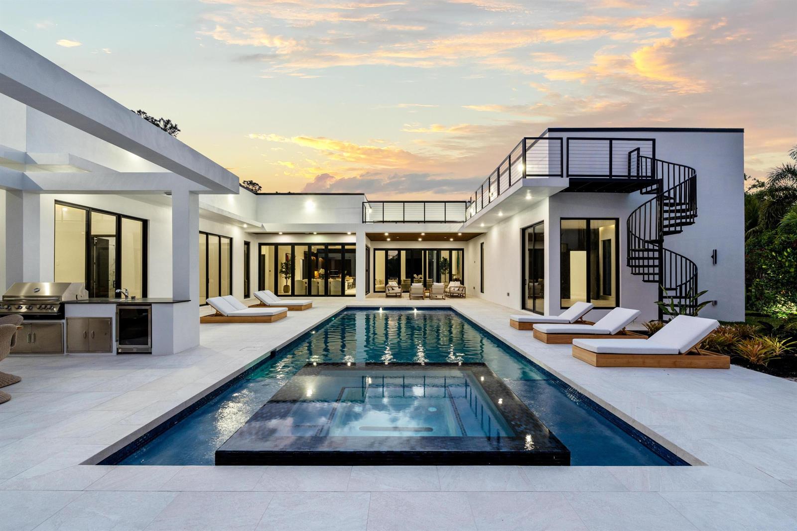 A modern white house with a pool, spa, outdoor kitchen, and spiral staircase at sunset — 6676 NW 66th Way, Parkland FL 33067, PARKLAND, FL