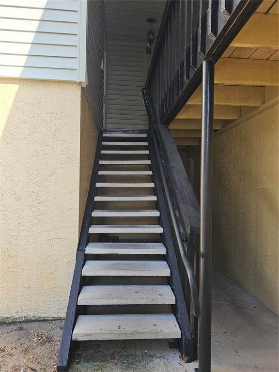 An exterior view of a staircase with concrete steps and black railings leading upward — 247 THORN TREE PLACE UNIT 247, BRANDON, FL