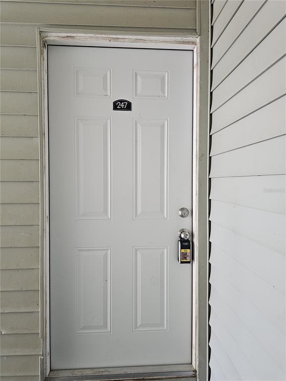 A white exterior door with the number 247 is set within light-colored horizontal siding — 247 THORN TREE PLACE UNIT 247, BRANDON, FL