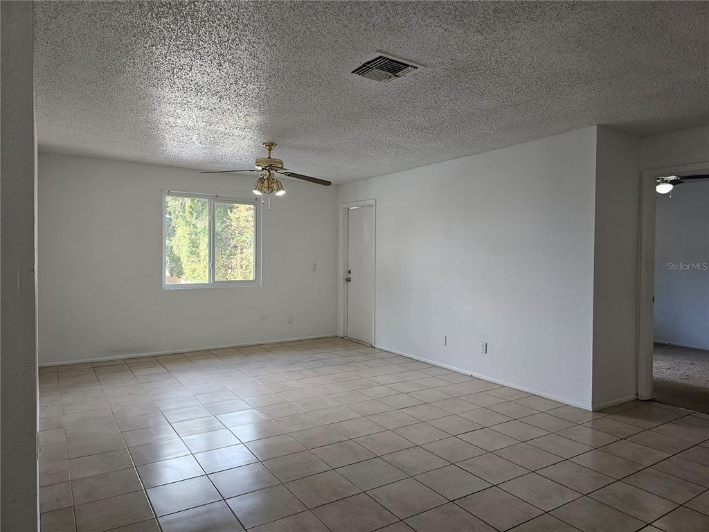 An empty room features white walls, a popcorn ceiling, a ceiling fan, and tiled flooring — 247 THORN TREE PLACE UNIT 247, BRANDON, FL