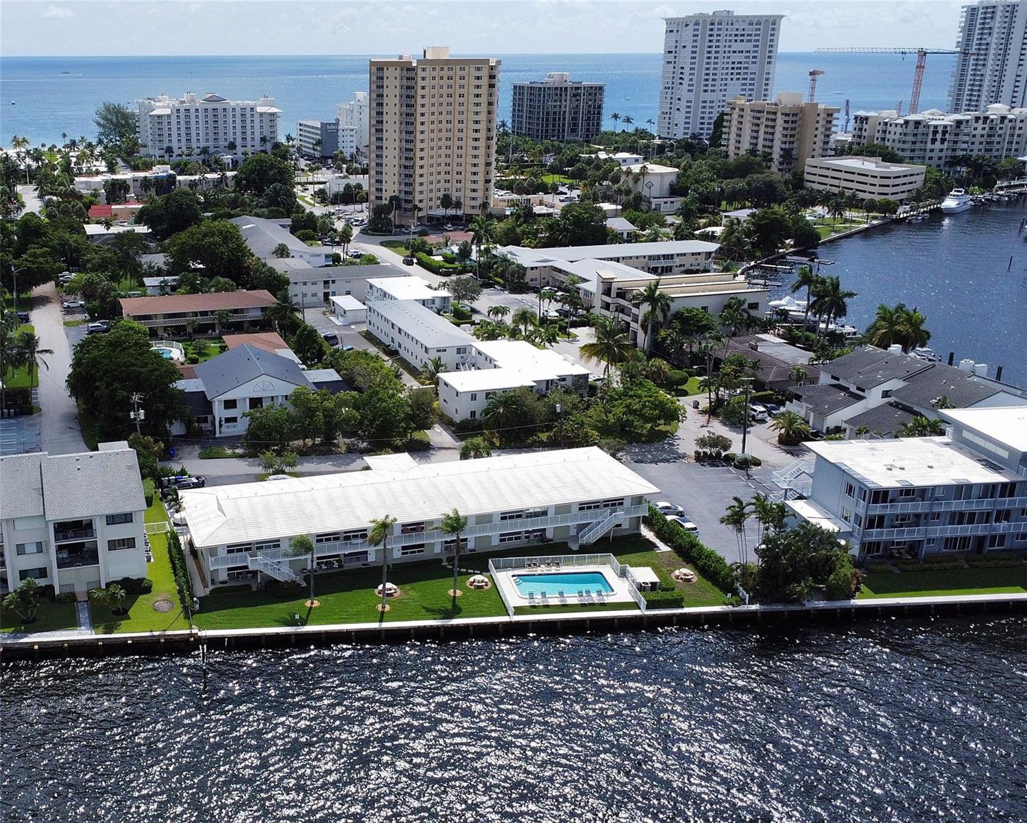 An aerial view shows a waterfront apartment complex with a swimming pool and surrounding buildings — 1105 S Riverside Drive # 205, Pompano Beach FL 33062, POMPANO BEACH, FL