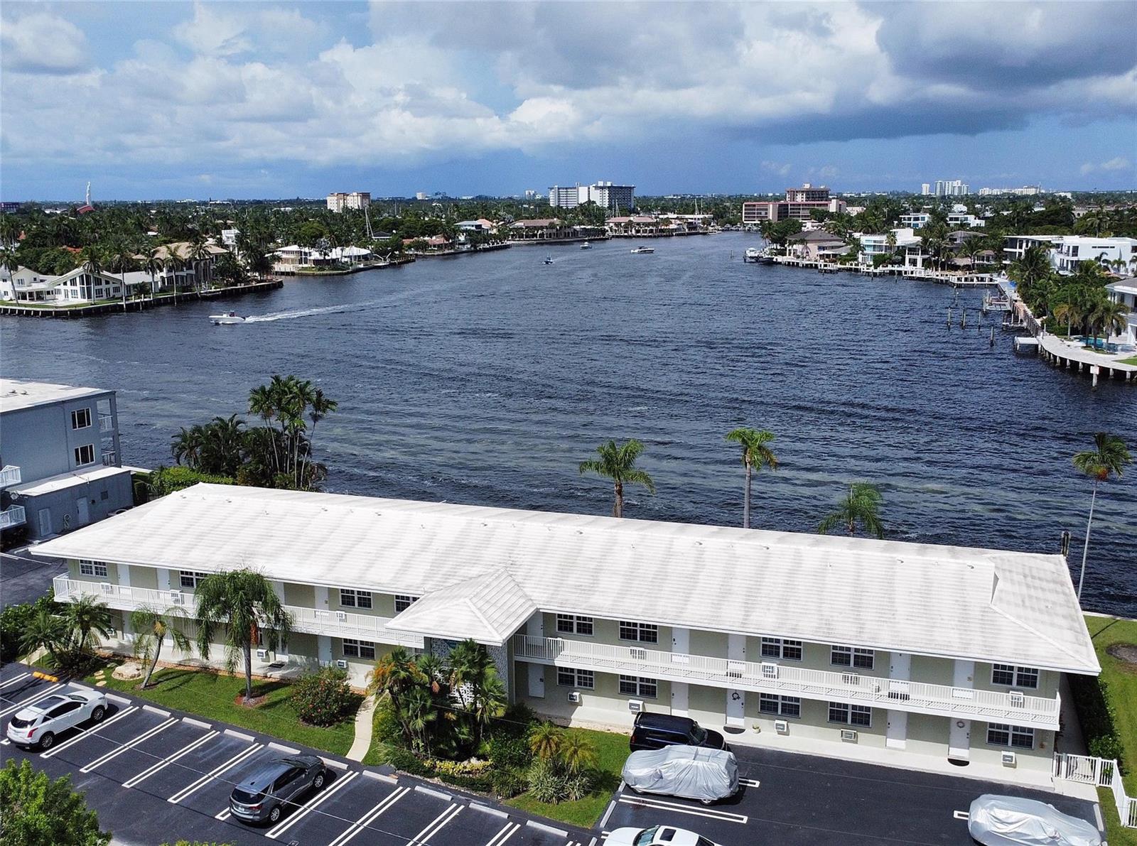 An aerial view shows a two-story apartment building with a parking lot beside a waterway — 1105 S Riverside Drive # 205, Pompano Beach FL 33062, POMPANO BEACH, FL