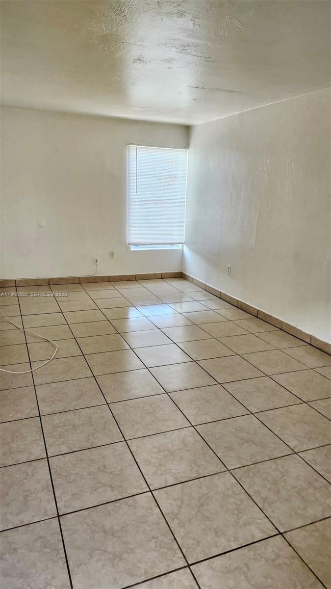 An empty room features beige tiled floors, white walls, and a single window with blinds — 6850 W 14th Ct # A15, Hialeah FL 33014, HIALEAH, FL
