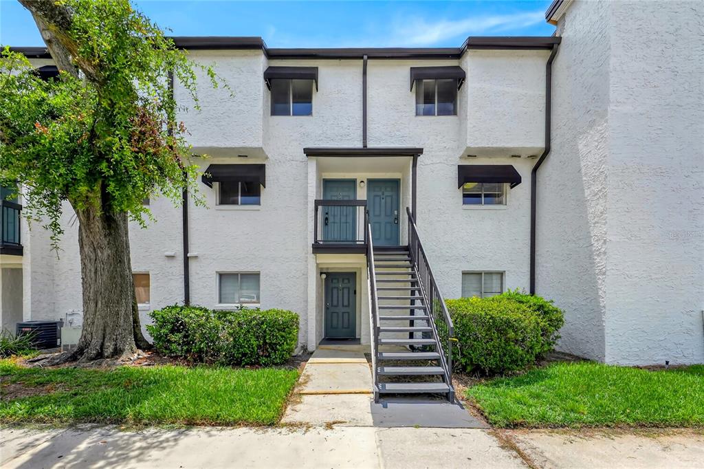 An exterior view of a two-story apartment building with stairs leading to the upper level — 4223 S. SEMORAN BLVD UNIT 6, ORLANDO, FL