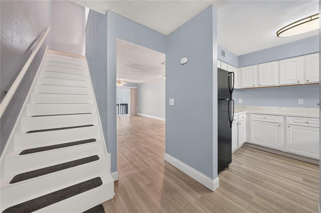 A staircase with dark treads leads upstairs next to a kitchen with white cabinets — 4223 S. SEMORAN BLVD UNIT 6, ORLANDO, FL