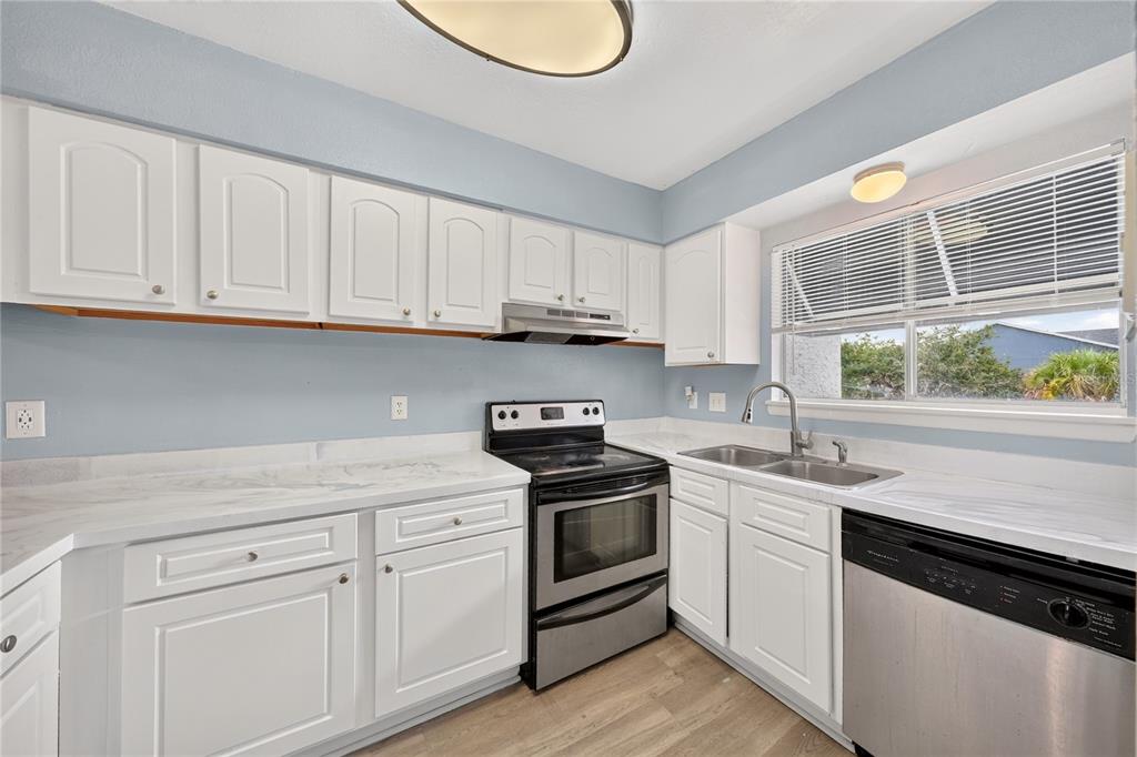 A kitchen with white cabinets, marble-look countertops, stainless steel appliances, and light blue walls — 4223 S. SEMORAN BLVD UNIT 6, ORLANDO, FL